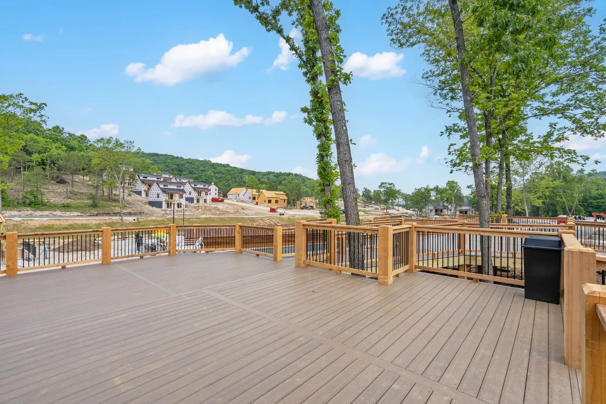 An inviting view from a wooden deck, overlooking newly built homes nestled among tall trees. The deck, ideal for socializing or relaxing, visually connects the private accommodations to the broader evolving neighborhood.