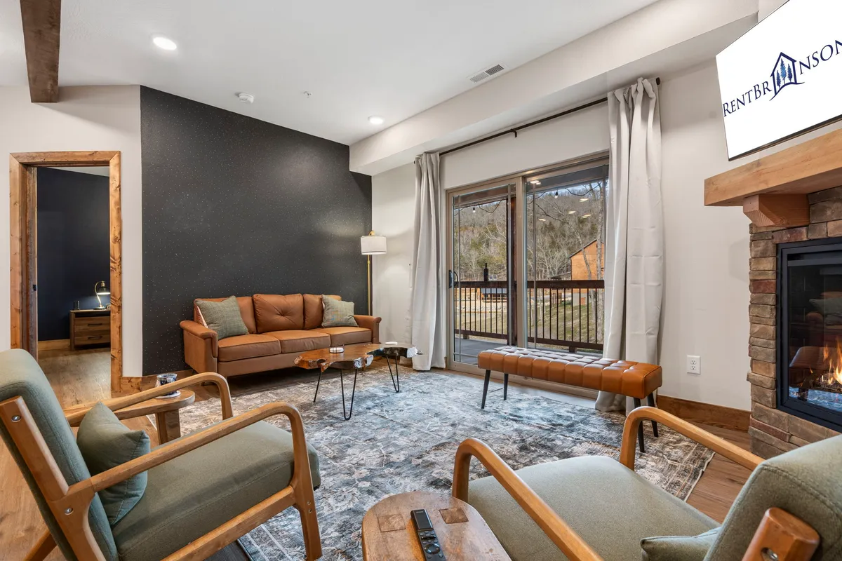 A cozy living room setup with a sofa, fireplace, and large windows looking out onto nature. The space is perfect for curling up with a book, enjoying warm drinks by the fire, or entertaining guests while basking in natural light.