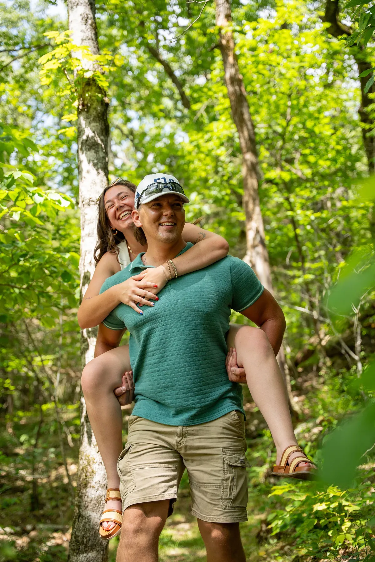 A couple enjoying each other's company while walking in a lush, natural setting. They are surrounded by verdant foliage, suggesting a peaceful trail or nature walk. Their expressions and body language convey happiness and a sense of carefree exploration together.