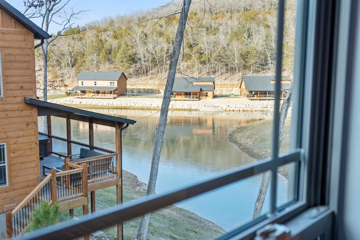 A tranquil water scene featuring wooden cabins reflected in calm waters, set against a backdrop of trees. The area invites fishing, boating, and peaceful nature walks, embodying the resort’s serene yet evolving spirit.